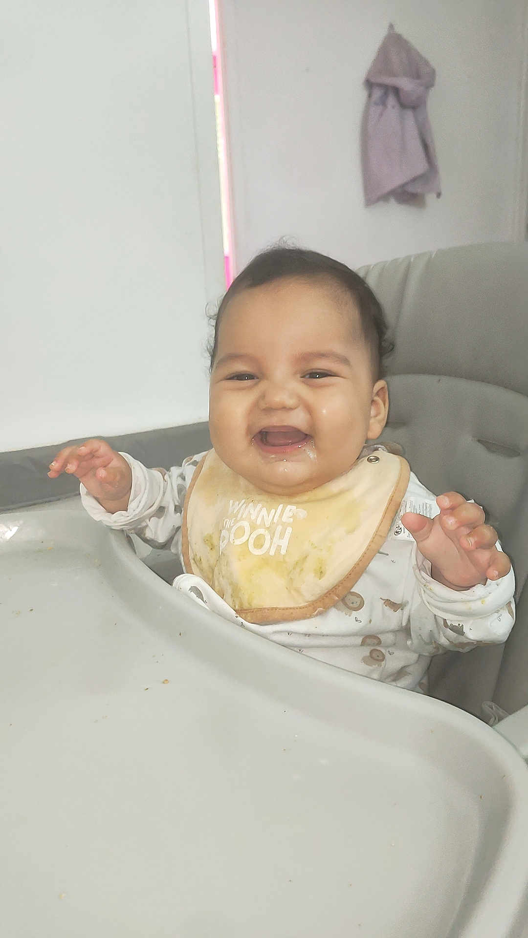 Imran participe au concours pour gagner de l'argent avec cette photo : baby, high_chair, bib, food, messy, smiling, drool, indoor, child, cute, happy, winnie_the_pooh, clothing, person, face, table, feeding, infant, young_child, hand