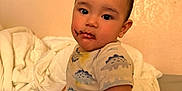 Kaitoa joined the competition — help win amazing prizes! toddler, child, baby, bed, bedding, onesie, dinosaur_pattern, messy_face, chocolate, indoor, person, cute, curious, skin, short_hair, sitting, soft_lighting, home, cozy, portrait
