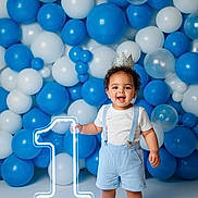 Azrah joined the competition — help win amazing prizes! toddler, child, birthday, balloons, blue, white, crown, suspenders, shorts, happy, smiling, barefoot, number_one, celebration, party, indoor, portrait, decorations, glowing, floor