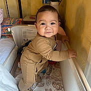 Kaelan a rejoint le concours — aidez-le/la à gagner de superbes lots ! baby, bedroom, blanket, bottle, child, cute, face, furniture, hand, home, indoor, infant, onesie, pattern, pillow, playpen, smiling, standing, wall, wood