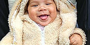 Kaelan a rejoint le concours — aidez-le/la à gagner de superbes lots ! baby, smiling, tongue_out, hoodie, fluffy_clothing, infant, cute, cushion, patterned_textile, seated, happy, child, warm_clothing, indoors, closeup, face, young_child, cozy, apparel, zipped_jacket