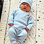 baby, newborn, sleeping, blue_outfit, knitted_clothing, hat, infant, peaceful, star_pattern, mattress, cute, cozy, small_hands, small_feet, indoors, portrait, child, resting, soft_light, sleep