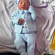 Albie is registered to the contest to win money with this photo: baby, newborn, infant, sleeping, hat, knitwear, pom_pom, blue_clothing, blanket, bed, soft_texture, cute, cozy, resting, person, child, indoors, apparel, warm_clothes, sleep