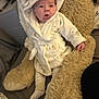 baby, infant, robe, hood, bear_prints, plush_toy, teddy_bear, soft_texture, bed, blanket, cute, child, indoor, sleepwear, cozy, expression, person, socks, comfort, resting
