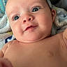 Elijah is registered to the contest to win money with this photo: baby, infant, face, blue_eyes, skin, blanket, soft_texture, curious_expression, close_up, lying_down, child, cute, portrait, naked_torso, indoors, person, newborn, young_child, happy, smiling