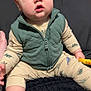 Declan is registered to the contest to win money with this photo: baby, child, dinosaur_pajamas, green_vest, drool, blue_eyes, sitting, blanket, indoor, cute, foot, hand, expression, portrait, clothing, young_child, infant, furniture, home, casual