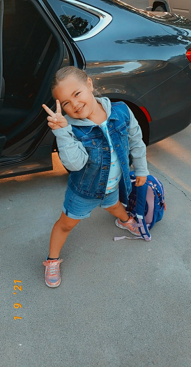 Harleigh joined the competition — help win amazing prizes! automotive_design, automotive_exterior, automotive_lighting, automotive_tire, bumper, car, electric_blue, head, hood, joy, leg, leisure, motor_vehicle, person, shorts, smile, sneakers, tire, toddler, trunk