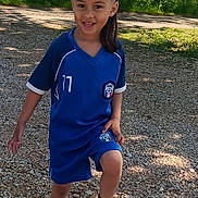 Tayden a rejoint le concours — aidez-le/la à gagner de superbes lots ! child, soccer_ball, blue_uniform, outdoor, gravel_path, greenery, sunlight, smiling, sport, footwear, shorts, jersey, nature, playing, happy, person, grass, daylight, casual, active