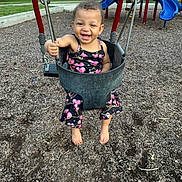 Londyn is registered to the contest to win money with this photo: toddler, child, swing, playground, smiling, barefoot, outdoor, daylight, wood_chips, play_equipment, happy, person, clothing, summer, fun, park, joyful, baby, seat, nature