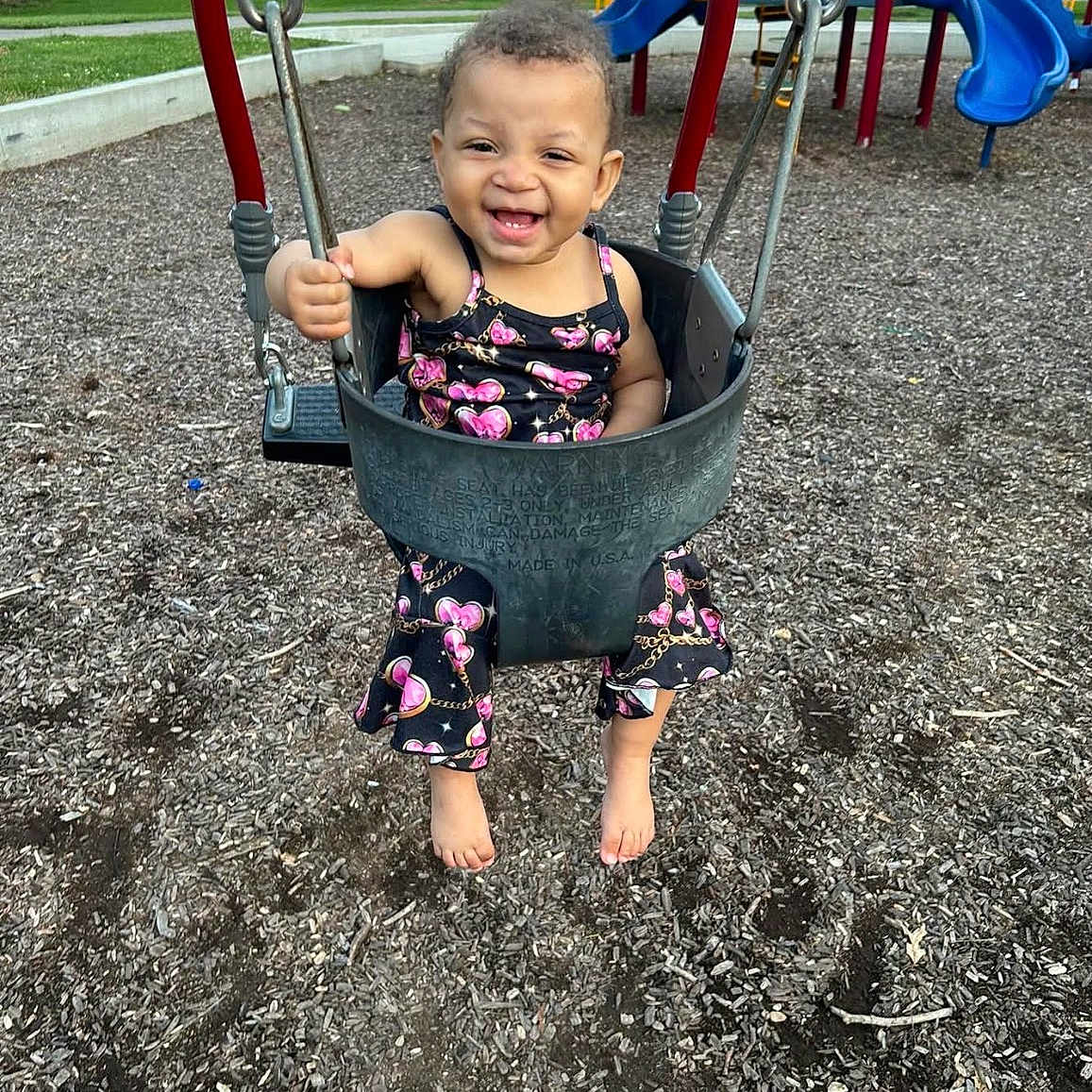 Londyn is registered to the contest to win money with this photo: toddler, child, swing, playground, smiling, barefoot, outdoor, daylight, wood_chips, play_equipment, happy, person, clothing, summer, fun, park, joyful, baby, seat, nature