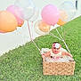 baby, basket, balloon, grass, flower_headband, outdoor, child, smiling, dress, pastel_colors, greenery, happy, cute, celebration, wicker, toddler, nature, fun, portrait, playful