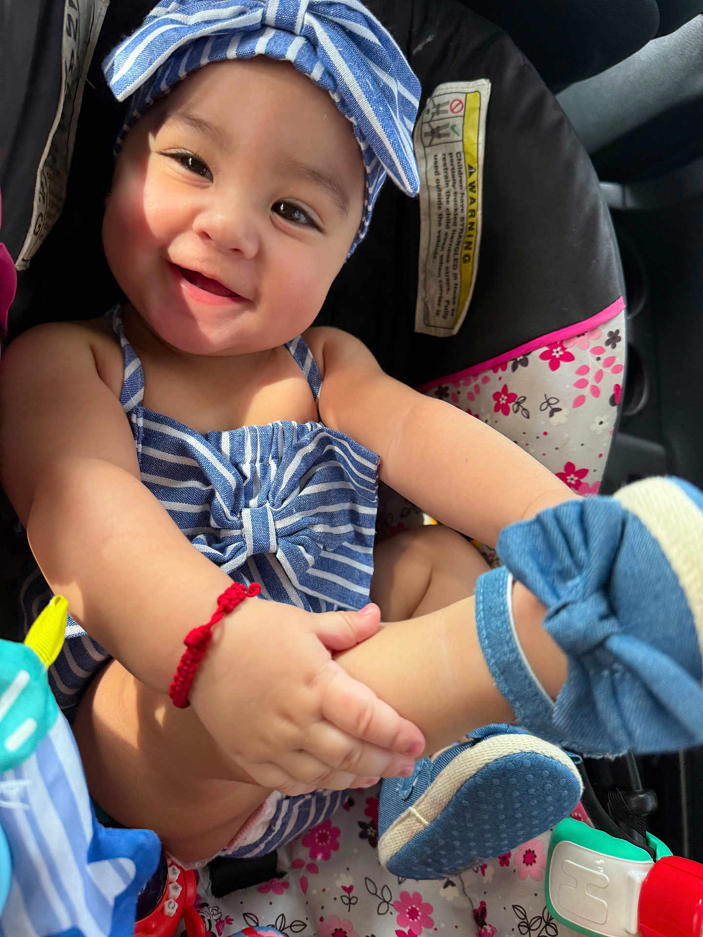Allyson is registered to the contest to win money with this photo: baby, smiling, blue_striped_clothing, headband, car_seat, floral_pattern, footwear, baby_shoes, red_bracelet, child, indoors, cute, happy, infant, playful, people, seatbelt, toddler, seat, portrait