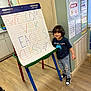 child, boy, classroom, easel, sign, welcome, vpk, eagles, class, 2026, floor, door, posters, wall, shoes, jeans, tshirt, smile, indoor, education