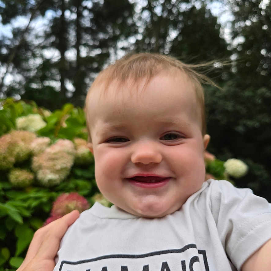 Brayden is registered to the contest to win money with this photo: baby, babylaughing, bodypart, clothing, face, finger, flower, hand, happy, head, laughing, mouth, person, petal, photography, plant, portrait, smile, t_shirt, teeth