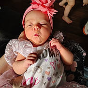 Davina joined the competition — help win amazing prizes! baby, infant, headband, pink, flower, dress, puckered_lips, cute, child, diaper, toddler, footwear, wooden_floor, person, hand, arm, fabric, pattern, indoor, candid