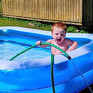 Nikko joined the competition — help win amazing prizes! child, red_hair, inflatable_pool, water, garden_hose, summer, outdoor, grass, wooden_shed, happy, playful, sunlight, backyard, splash, water_spray, bare_chest, fun, daytime, nature, person