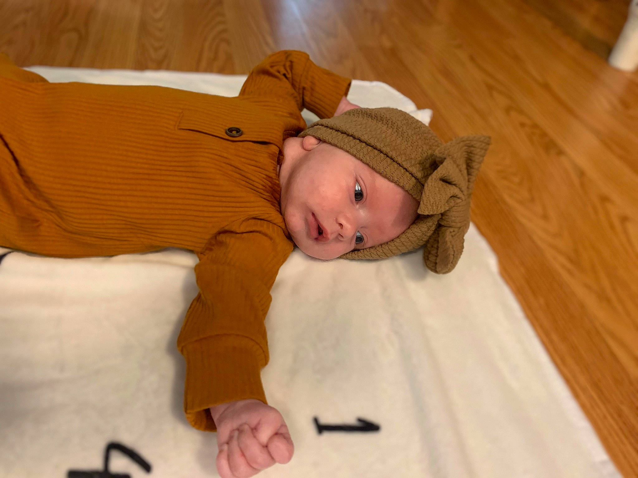 Bailey is registered to the contest to win money with this photo: baby, baby_toddler_clothing, comfort, face, flooring, fun, hardwood, hat, headgear, headwear, linens, person, room, skin, sleeve, smile, sun_hat, toddler, varnish, wood