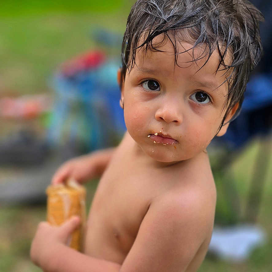 Ohtli is registered to the contest to win money with this photo: bare_chest, blue_shorts, casual, child, crackers, curious, daylight, expression, grass, holding, messy_face, nature, outdoor, person, portrait, snack, summer, toddler, wet_hair, young_child