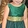 child, girl, crown, dress, green_dress, gold_belt, smile, party, celebration, indoor, person, young_child, festive, happy, portrait, event, table, water_bottle, people, hairstyle