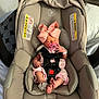 newborn, baby, car_seat, pacifier, pink_bow, infant, sleeping, clothing, baby_wear, seat_belt, indoor, soft_fabric, child, cute, resting, tiny_feet, hospital_band, car_seat_padding, infant_clothing, baby_accessory