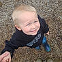 child, blond_hair, black_hoodie, blue_boots, holding_hands, outdoor, gravel, smiling, looking_up, adult, jeans, green_boots, person, casual_clothing, ground, cute, happy, daylight, portrait, toddler