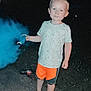 child, toddler, barefoot, blue_smoke, night, outdoor, shorts, tshirt, gravel, toy, smoke, holding, standing, curious, person, casual_clothing, light_skin, short_hair, dark_background, playful