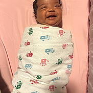 Icelee is registered to the contest to win money with this photo: baby, blanket, child, childcare, cozy, cute, fabric, face, handprint, happy, indoors, infant, lying_down, newborn, pink, portrait, sleeping_area, smile, soft, wrapped