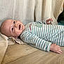 baby, infant, smile, drool, striped_onesie, wooden_floor, beige_fabric, happy, lying_down, child, cute, portrait, skin, hand, head, face, clothing, indoors, young, relaxed