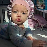 Maze joined the competition — help win amazing prizes! baby, infant, child, face, blue_eyes, pink_bonnet, onesie, bed, blanket, toy, indoor, soft_light, curious, hands, crawling, pastel_colors, cozy, portrait, young_child, expression