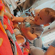 William is registered to the contest to win money with this photo: baby, blanket, toy, indoor, child, person, floor, carpet, clothing, sitting, arm, leg, window, light, furniture, home, curious, colorful, play, infant