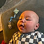 Cooper is registered to the contest to win money with this photo: baby, infant, checkered_clothing, pacifier, couch, smiling, happy, face, skin, hand, indoors, child, cute, expression, person, young_child, comfort, soft_lighting, wearing, sitting