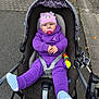 Deborah-Ema a rejoint le concours — aidez-le/la à gagner de superbes lots ! baby, child, stroller, purple_clothing, pacifier, hat, unicorn, toy, outdoor, sidewalk, blue_eyes, socks, baby_seat, cute, infant, winter_wear, playful, street, person, portrait