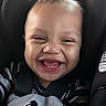 baby, child, car_seat, blanket, mickey_mouse, smiling, happy, face, infant, clothing, seatbelt, portrait, cute, indoor, young_child, head, person, baby_boy, black_and_white_clothing, digital_clock