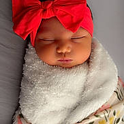 Princess Leilani is registered to the contest to win money with this photo: baby, sleeping, red_bow, headband, blanket, floral_pattern, cozy, wrapped, infant, cute, peaceful, portrait, indoors, child, soft_texture, newborn, face, adorable, resting, skin