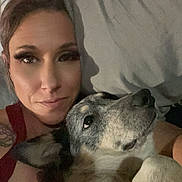 Athena joined the competition — help win amazing prizes! woman, dog, face, closeup, bedroom, pillow, snuggling, pet, lying_down, casual, indoor, portrait, relaxed, human, animal, companion, affection, tattoo, red_tank_top, expression