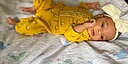 Skyler is registered to the contest to win money with this photo: baby, infant, yellow_clothing, headband, bow, lying_down, blanket, patterned, cute, face, skin, small_hands, footwear, indoors, soft_texture, child, newborn, portrait, sleepwear, resting