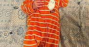 Lorenzo is registered to the contest to win money with this photo: baby, infant, child, lying_down, pacifier, orange_onesie, striped_clothing, floral_blanket, blanket, portrait, face, wide_eyed, indoor, cozy, textile, patterned_background, hand, arm, sleepwear, photograph