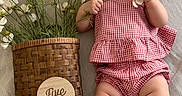 Mai joined the competition — help win amazing prizes! baby, infant, child, flower, basket, plaid_clothing, gingham, milestone, wooden_plaque, laying_down, soft_fabric, cute, smiling, skin, legs, arms, hand, natural_light, indoor, portrait