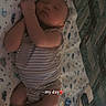 newborn, baby, infant, sleeping, lying_down, portrait, face, closed_eyes, blanket, crib, onesie, striped_clothing, bedroom, indoor, cozy, peaceful, cute, baby_feet, soft_lighting, text_overlay