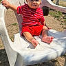 baby, child, infant, outdoor, chair, plastic_chair, red_clothing, striped_shirt, shorts, sitting, smiling, face, bare_feet, backyard, grass, fence, sunlight, portrait, playful, family_photo