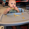 toddler, child, baby, high_chair, restaurant, fast_food, fries, snacking, eating, food, sandwich, tray, portrait, smiling, face, hands, indoor, dining, adult, background