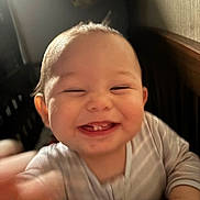 Lyndon is registered to the contest to win money with this photo: baby, smiling, teeth, face, hand, infant, joy, happiness, indoor, blur, closeup, person, child, cute, young, expression, blurred_motion, wearing, striped_clothing, head