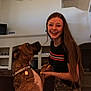 Bubba joined the competition — help win amazing prizes! woman, dog, indoor, living_room, smiling, playing, long_hair, camouflage_pants, black_shirt, ceiling_fan, shelf, furniture, pet, bonding, happy, home, brown_dog, collar, friendly, interaction