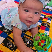 Journey is registered to the contest to win money with this photo: baby, child, headband, toy, quilt, colorful, indoor, face, hand, clothing, blue, pink, pattern, soft_toys, floor, person, crawling, infant, cute, playtime