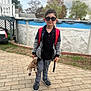 Elliot joined the competition — help win amazing prizes! child, boy, sunglasses, backpack, plush_toy, giraffe, paved_patio, outdoor, casual_clothing, jacket, pants, sneakers, toy, fence, trees, cloudy_sky, residential_area, smiling, standing, person
