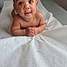 baby, infant, curly_hair, big_eyes, medical_table, paper_cover, skin, child, cute, portrait, indoors, expression, hands, lying_down, young_child, looking_up, healthcare, examination, room, curiosity