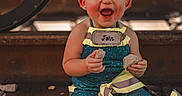 Dixianna is registered to the contest to win money with this photo: blue_outfit, bow, casual_clothing, child, cute, daylight, dirt, fun, happy, outdoor, person, playful, portrait, reflective_ribbons, rocks, sitting, smiling, toddler, train_tracks, young