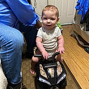 Donnie joined the competition — help win amazing prizes! toddler, child, toy_vehicle, indoor, carpet, wood_floor, person, adult, jeans, slippers, clothing, door, handlebars, play, room, furniture, footwear, baby, smile, supervision