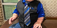 Donnie is registered to the contest to win money with this photo: toddler, child, boy, portrait, indoor, table, vest, tie, blue_shirt, jeans, socks, brick_wall, window, restaurant, casual, cute, baby, smiling, person, seated