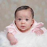 Avani is registered to the contest to win money with this photo: baby, infant, child, portrait, sitting, pink_dress, ruffles, pearl_necklace, white_fur, fluffy_blanket, face, eyes, hair, serious_expression, indoor, studio, close_up, photography, soft_lighting, furniture